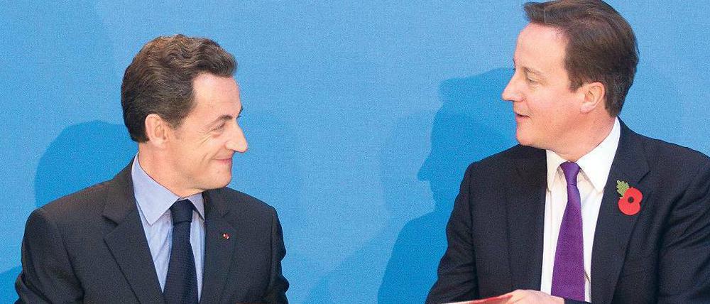 Sarkozy (l.) und Cameron machen aus der Finanznot eine militärische Tugend.