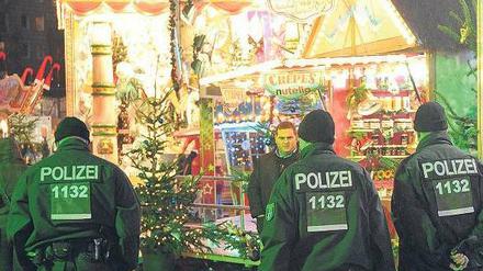Grüne Weihnachten. Polizeibeamte gehen auf einem Weihnachtsmarkt in der Nähe des Alexanderplatzes in Berlin entlang. 