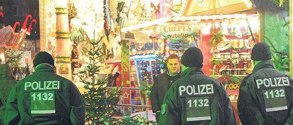 Grüne Weihnachten. Polizeibeamte gehen auf einem Weihnachtsmarkt in der Nähe des Alexanderplatzes in Berlin entlang. 