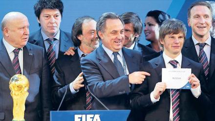 Grinsen mit Umschlag. Russlands Sportminister Witali Mutko (Mitte) jubelte, Nationalmannschaftskapitän Andrej Arschawin durfte das Votum in die Luft halten. Foto: AFP