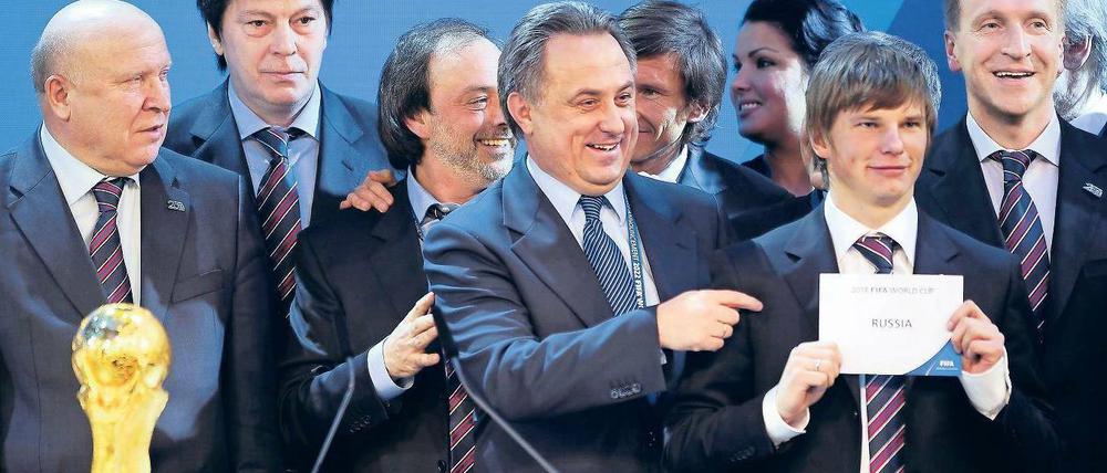 Grinsen mit Umschlag. Russlands Sportminister Witali Mutko (Mitte) jubelte, Nationalmannschaftskapitän Andrej Arschawin durfte das Votum in die Luft halten. Foto: AFP