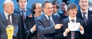 Grinsen mit Umschlag. Russlands Sportminister Witali Mutko (Mitte) jubelte, Nationalmannschaftskapitän Andrej Arschawin durfte das Votum in die Luft halten. Foto: AFP
