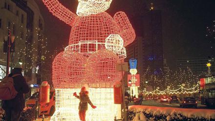 Schnee, schöne Lichter und Shopping-Stress: Auf dem Kurfürstendamm suchen Berliner nach den letzten Weihnachtsgeschenken. Der Handel reagiert zum Teil mit längeren Öffnungszeiten.
