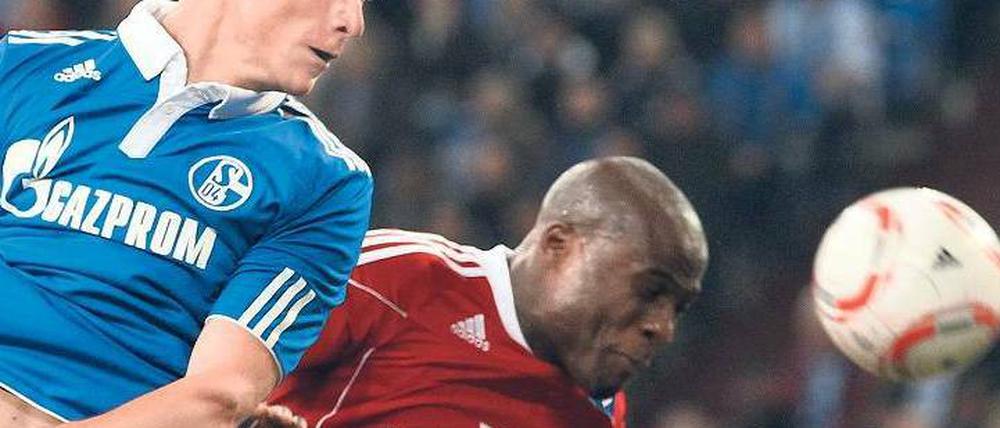 Nicht auf Augenhöhe. Der Schalker Benedikt Höwedes (l.) beim Kopfballduell mit dem Hamburger Guy Demel. Foto: dpa