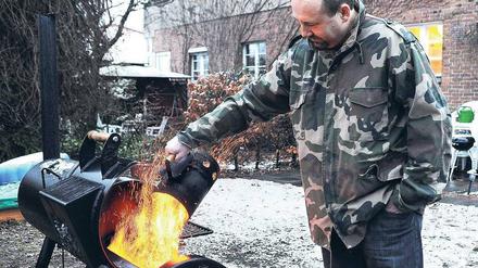 Vereinigtes Braten. Grillsportler Marc Riemer beim Grillen im winterlichen Garten.