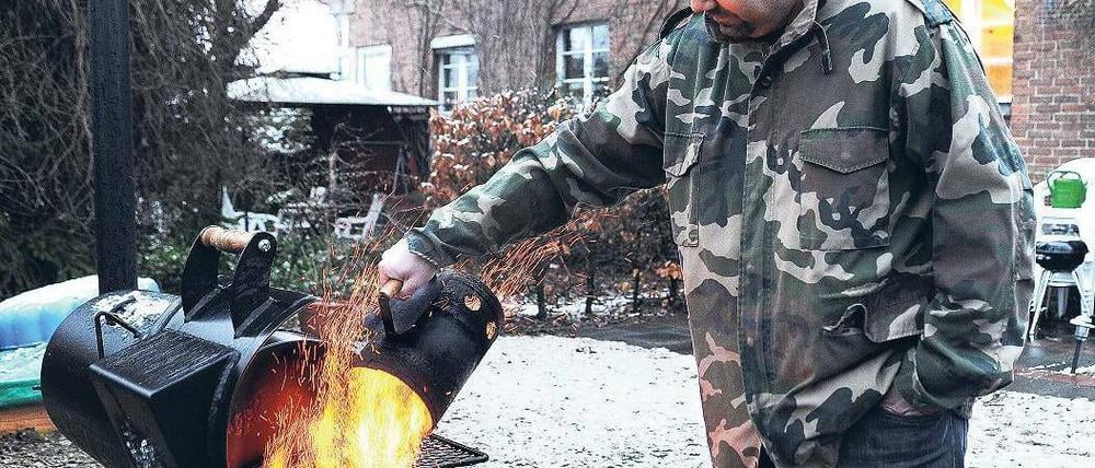 Vereinigtes Braten. Grillsportler Marc Riemer beim Grillen im winterlichen Garten. 