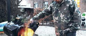 Vereinigtes Braten. Grillsportler Marc Riemer beim Grillen im winterlichen Garten. 