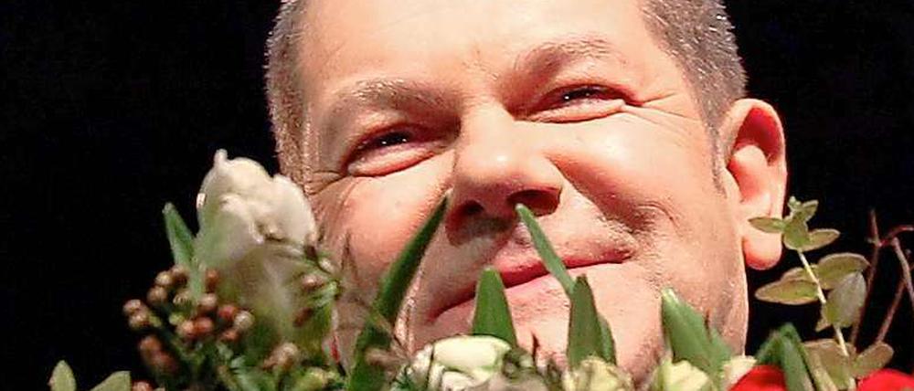 Ein bisschen Lächeln kann jeder: Olaf Scholz hinter Blumen.