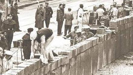 Es geschah in Berlin: Bewacht von Volkspolizisten, mussten Maurer am 13. August 1961 die Steine für das sozialistische Schandwerk zusammenfügen. 