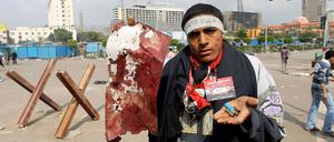 Ein Demonstrant in Kairo hält Patronenhülsen und einen angeblich Blut getränkten Fetzen in den Händen.