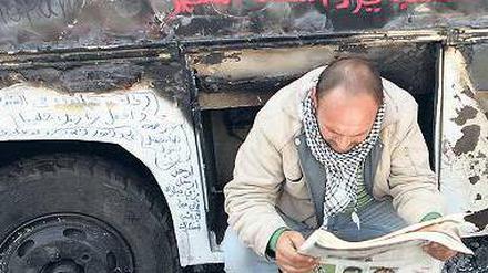 Spuren. Ein Zeitungsleser vor einem Bus-Wrack auf dem Tahrir-Platz. 