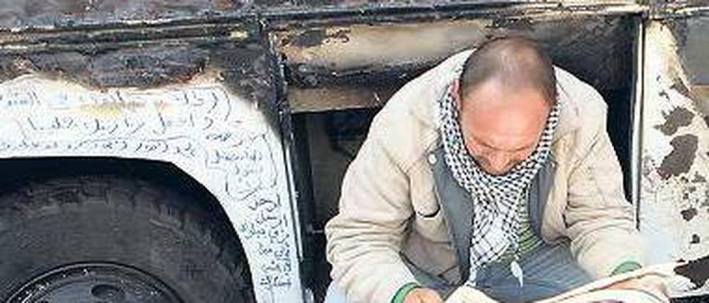 Spuren. Ein Zeitungsleser vor einem Bus-Wrack auf dem Tahrir-Platz. 