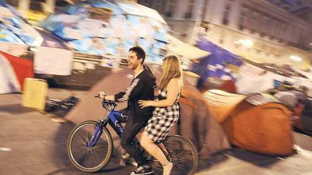 Revolution auf Spanisch. Ein junges, Fahrrad fahrendes Pärchen, auf der Puerta del Sol in Madrid. 