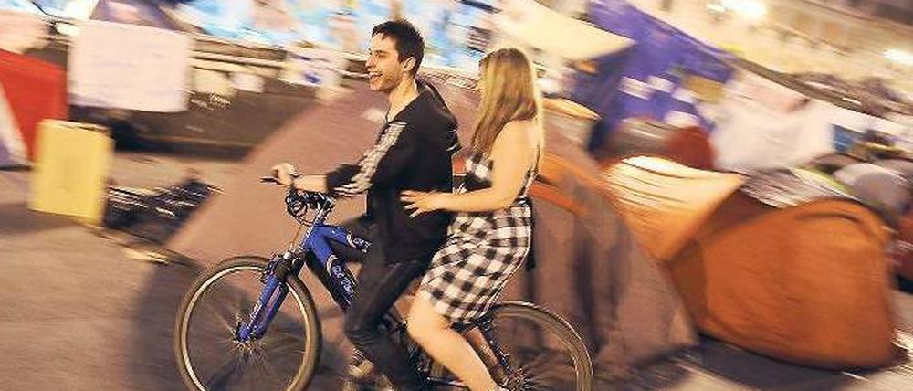 Revolution auf Spanisch. Ein junges, Fahrrad fahrendes Pärchen, auf der Puerta del Sol in Madrid. 