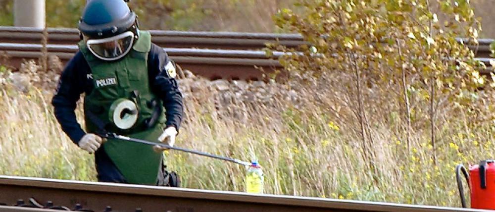 Ein Polizist stellt am Mittwoch in Berlin-Staaken an der ICE-Strecke Berlin - Hamburg Teile eines Brandsatzes sicher. An der Strecke wurde am Vormittag ein Brandsatz entdeckt, der bereits gezündet war. Wann der Behälter brannte, war zunächst unklar, sagte ein Polizeisprecher.
