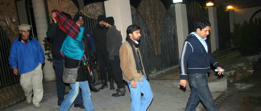 Pakistanische Mitarbeiter der Welthungerhilfe eskortieren eine deutsche Kollegin, nachdem sie das Wanderlagen besuchten, aus welchem ein Deutscher und ein Italiener entführt worden waren.