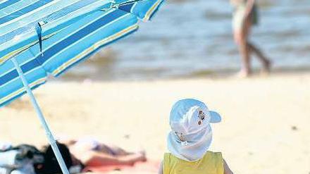 Kinder, war das schön. Gut bemützt und im Schatten platziert ließ es sich aushalten an diesem Sonnabend im Strandbad Wannsee. Manche zog es sogar schon ins Wasser – dabei hatte das gerade einmal 14 Grad. Foto: dapd/Maja Hitij