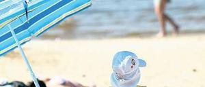 Kinder, war das schön. Gut bemützt und im Schatten platziert ließ es sich aushalten an diesem Sonnabend im Strandbad Wannsee. Manche zog es sogar schon ins Wasser – dabei hatte das gerade einmal 14 Grad. Foto: dapd/Maja Hitij
