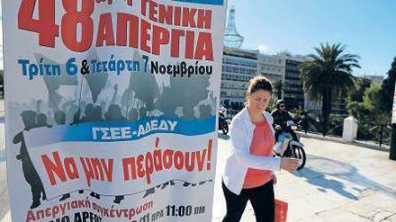 Eine Athenerin geht am Syntagma-Platz im Zentrum der Hauptstadt an einem Plakat vorbei, auf dem der bevorstehende Generalstreik angekündigt wird.