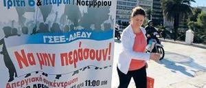 Eine Athenerin geht am Syntagma-Platz im Zentrum der Hauptstadt an einem Plakat vorbei, auf dem der bevorstehende Generalstreik angekündigt wird.
