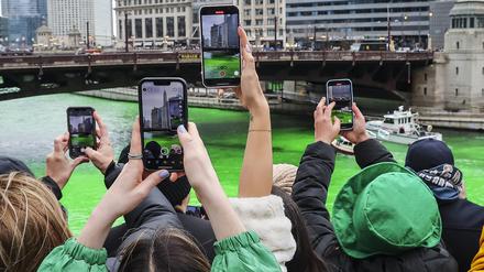 Zuschauer machen Fotos, während der Chicago River anlässlich der Feierlichkeiten zum St. Patrick’s Day in der Innenstadt von Chicago grün gefärbt wird.
