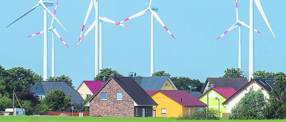 Ganz dicht stehen Windräder eines Windenergieparks hinter Einfamilienhäusern nahe Nauen (Brandenburg).