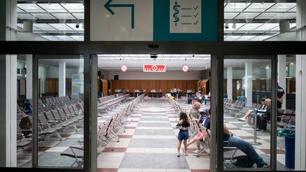 Menschen sitzen in der Ankunftshalle für Geflüchtete im Landesamt für Flüchtlingsangelegenheiten. 