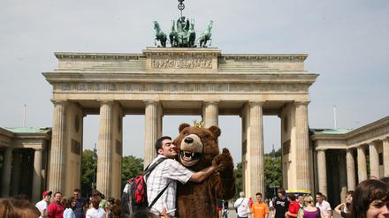 Touristen fotografieren sich mit einem Berliner Bären am Brandenburger Tor in Berlin-Mitte.