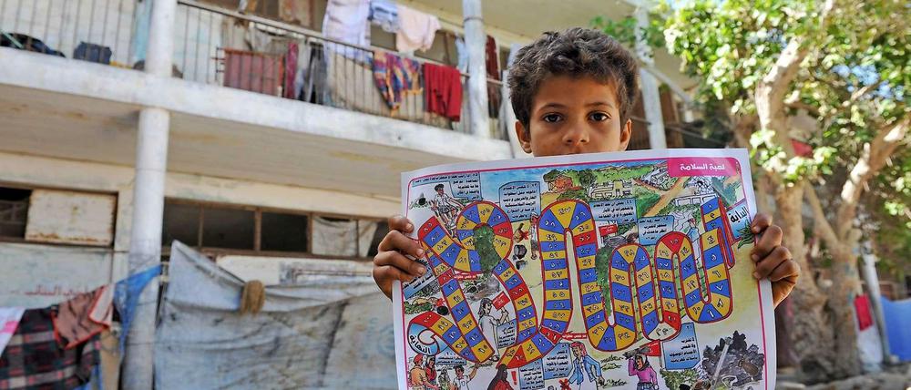 Der elfjährige Ahmed mit einem Spiel, das Flüchtlingskinder vor den Gefahren von Landminen warnen soll.