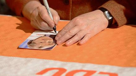 Was ist die Handschrift der CDU? Angela Merkel unterschreibt Autogrammkarten.