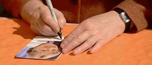 Was ist die Handschrift der CDU? Angela Merkel unterschreibt Autogrammkarten.