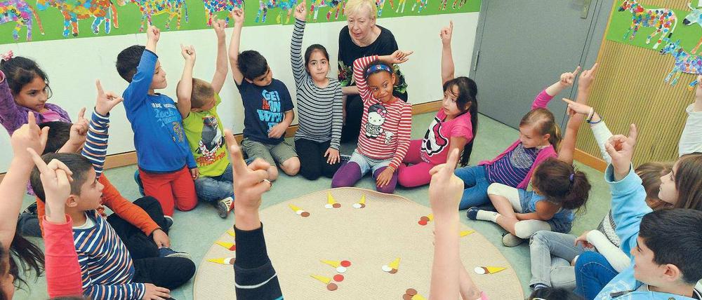 Die Leiterin der Herman-Nohl-Schule aus Britz, Ilona Bernsdorf, sitzt mit Kindern einer Jül-Klasse an einem Mathelernteppich.