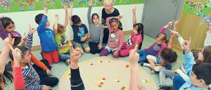 Die Leiterin der Herman-Nohl-Schule aus Britz, Ilona Bernsdorf, sitzt mit Kindern einer Jül-Klasse an einem Mathelernteppich.