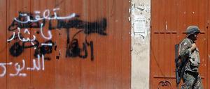 "Bashar, du wirst fallen" steht an der Wand, an der gerade ein Soldat vorbeigeht. Gemeint ist der syrische Machthaber Bashar al Assad. 