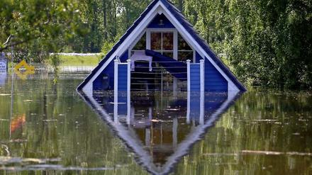 Hausdach in blau ragt aus Wasser mit Spiegelung