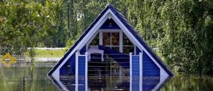 Hausdach in blau ragt aus Wasser mit Spiegelung