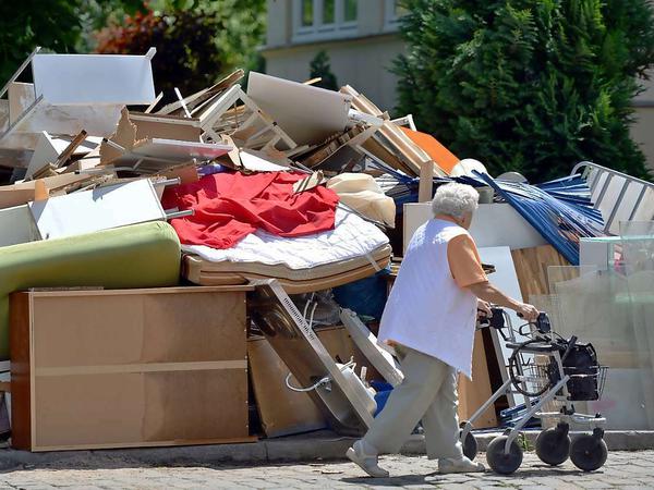 Frau mit Rollator läuft an Sperrmüllberg vorbei