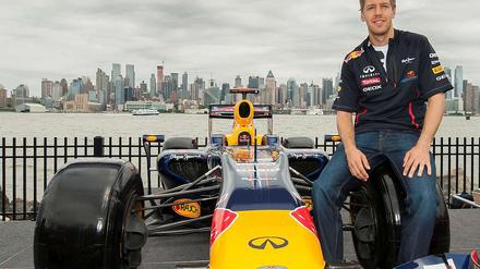 Sebastian Vettel sitzt auf dem reifen seines Formel-1-Autos.