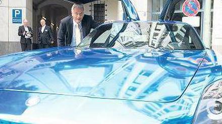Minister Ramsauer unter der geöffneten Tür eines blauen Flügeltürers.