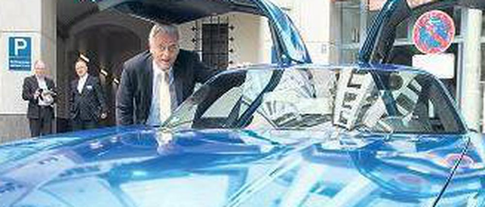 Minister Ramsauer unter der geöffneten Tür eines blauen Flügeltürers.