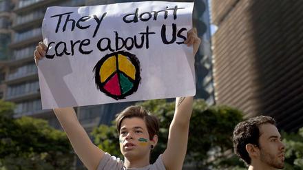 Ein Jugendlicher hält ein Transparent mit der Aufschrift "They don`t care about us" und einem Friedenszeichen in die Höhe.