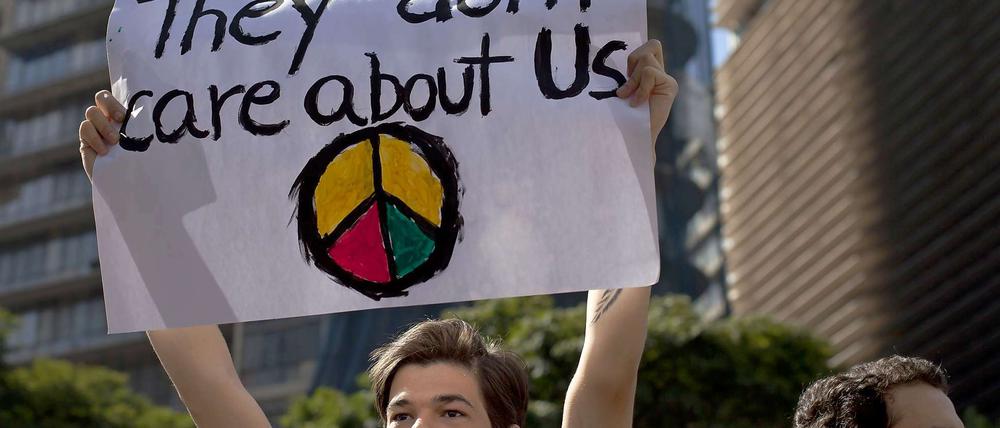 Ein Jugendlicher hält ein Transparent mit der Aufschrift "They don`t care about us" und einem Friedenszeichen in die Höhe.