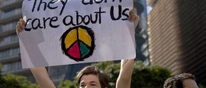 Ein Jugendlicher hält ein Transparent mit der Aufschrift "They don`t care about us" und einem Friedenszeichen in die Höhe.