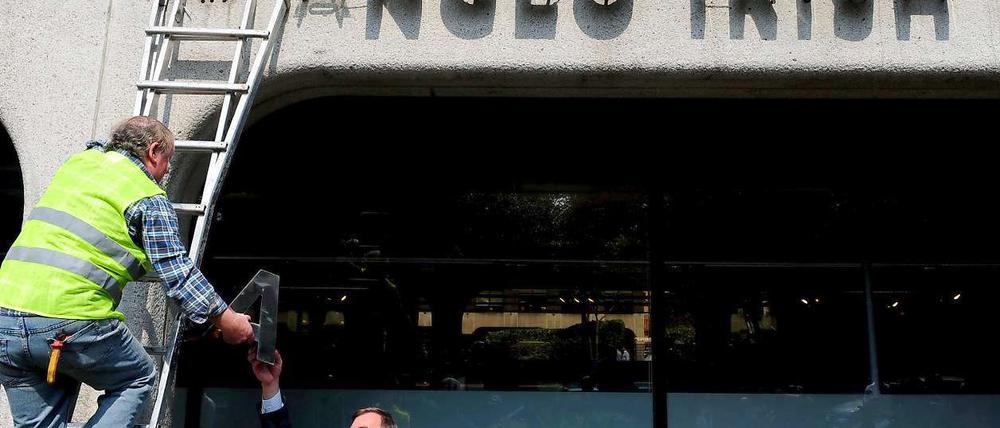 Ein Mann auf einer Leiter demontiert den Schriftzug der bankrotten Anglo Irish Bank. 