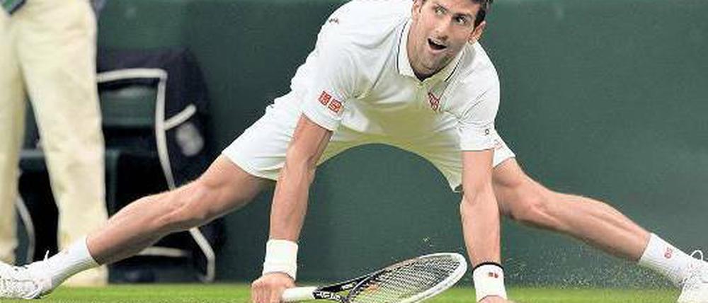 Novak Djokovic steht fast im Spagat auf dem Rasen on Wimbledon.