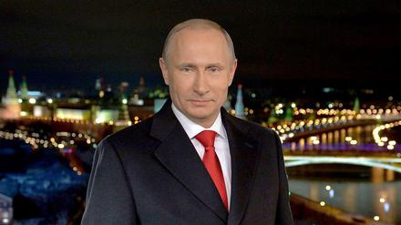 Der russische Präsident Wladimir Putin bei seiner Neujahrsansprache.  Im Hintergrund ist Moskau bei Nacht zu sehen.