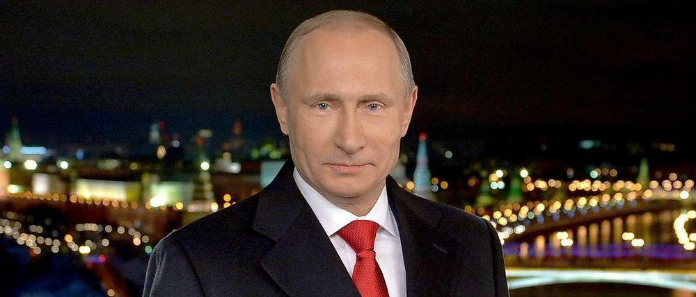 Der russische Präsident Wladimir Putin bei seiner Neujahrsansprache. Im Hintergrund ist Moskau bei Nacht zu sehen.