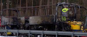 Ein Mitarbeiter des ADAC steht am Montag auf der Autobahn 13 nahe Ortrand (Brandenburg) in einem ausgebrannten dänischen Reisebus.