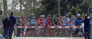 Bahnschranke mit Radrennen. Das Feld wartet auf den Zug. 