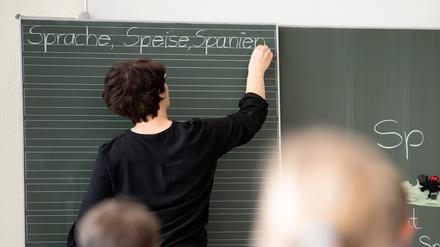 ARCHIV - 13.05.2019, Baden-Württemberg, Remshalden: Eine Lehrerin schreibt in einer Grundschule Worte an eine Tafel. In den Schulen gibt es nach Ansicht des Deutschen Lehrerverbands noch keine Entspannung der Corona-Lage. Foto: Sebastian Gollnow/dpa +++ dpa-Bildfunk +++
